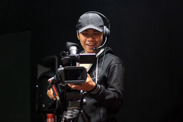 Cameraman smiling while operating camera on tripod in studio