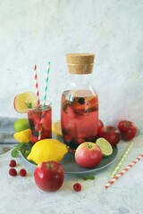 Fototapeta na wymiar Detox drink from apples, berries, mint and citrus in glasses and in a decanter, on the table, seasonal drinks from organic natural ingredients