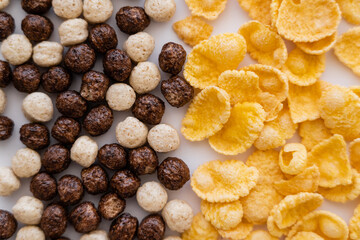 close up of cereal balls with different flavors near corn flakes isolated on white.