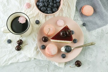 A slice of fruit cake with cream on a plate, decorated with berries, a cup of coffee, meringue, on the kitchen table, homemade natural food and drink, sweet dessert