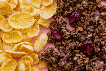 close up view of crispy corn flakes and crunchy granola on pink.