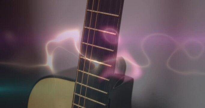 Animation of white, blue and pink light trails over acoustic guitar on smokey background