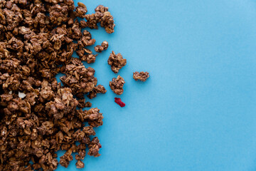 top view of crunchy and sweet oat granola isolated on blue.