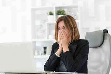 Surprised business woman looking at laptop and shocked after bad news about business. Bankruptcy...