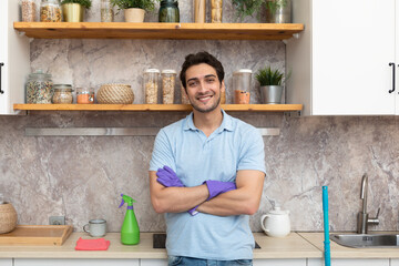 Handsome and cheerful man cleaning kitchen. Young husband in household concept	