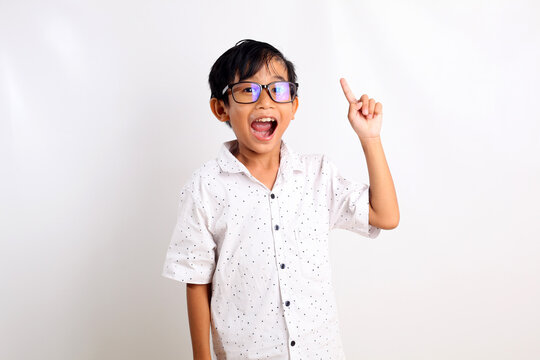 Adorable asian boy wearing glasses standing while getting an idea and pointing his finger.