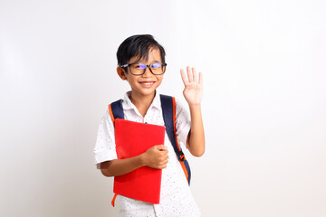 Happy asian schoolboy standing while showing four fingers, carrying a book and school bag