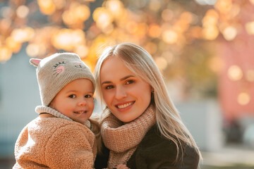 Obraz premium Happy mother and daughter are walking in the autumn park. Beautiful family in warm clothes. Fall.