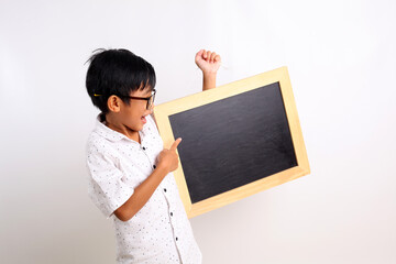 Fototapeta na wymiar Happy asian schoolboy standing while showing a blank blackboard. Isolated on white background