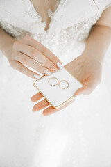 Wedding rings on a box in the hands of the bride