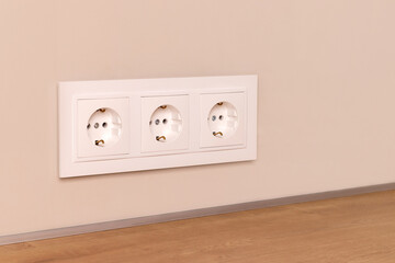 Group of white european electrical outlets on modern beige wall. Selective focus