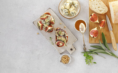 Tasty bruschetta with ripe figs, blue cheese, pine nuts and honey on a light background. top view, copy space