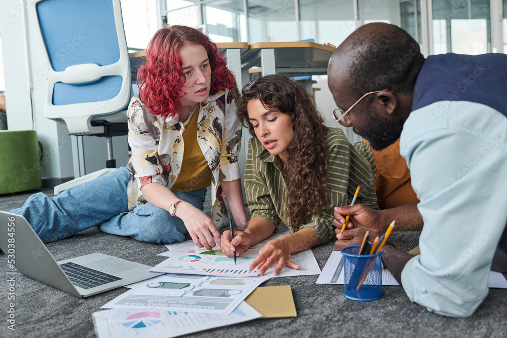 Aufkleber two young confident women pointing at financial document while one of them explaining graphic data t