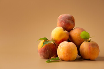 Fresh ripe juicy whole and cut red peaches on rough brown background.