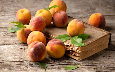 Ripe peaches on book and wooden background