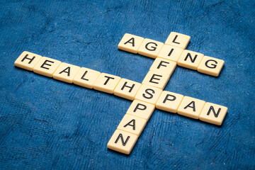 aging, lifespan and healthspan crossword in ivory letter tiles against textured handmade paper, age...