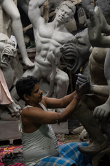 A man painting Durga idol with use of selective focus on a particular part of the man with rest of the man, the idol and everything else blurred. Kolkata, West Bengal, India - 11.09.2022