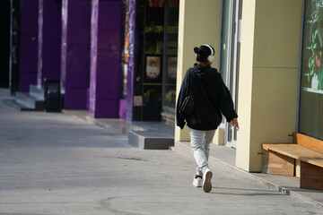 the teenage girl walking down the street listening to music. street photography.