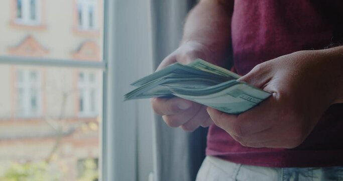 close-up of male hands counting a stack of hundred-dollar US banknotes. young man redraws money, a salary in the hands of one hundred dolor bills. 