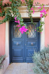 Traditional greek house with flowers in Corfu island, Greece. Blue door surrounded by magenta flowers