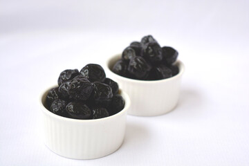 dried plums in bowls with white background