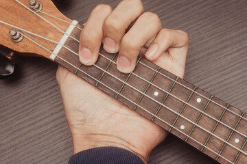 ukulele in close up with hand placing chords. The chord is G. Portable string instrument. Music...