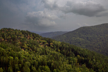 Autumn landscape, forested mountains, cloudy sky.