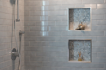 Modern bathroom details of gray tile shower with decorative insets and chrome finishes.