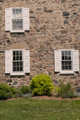 Fototapeta na wymiar Windows with shutters on old stone house.