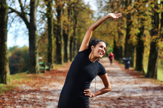 positive woman stretching outdoors preparing for exercise in sportswear