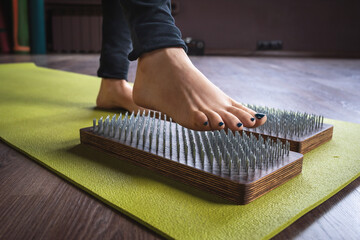 Women's leg steps on sadhu board with nails for yoga, massage-themed concept
