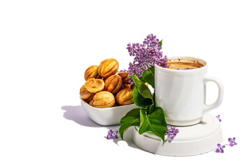 Cup of coffee and cookies in the shape of walnuts with cream filling isolated on a white background