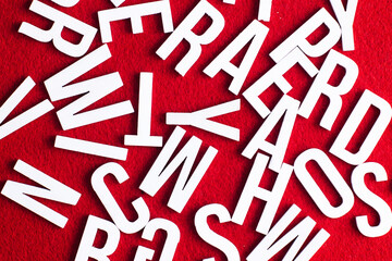 Alphabet background. Random order letters. Typography texture. Wooden letters on red fabric.