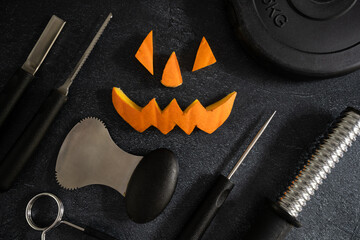 Dumbbell barbell weight plate with Halloween pumpkin pieces cut out. Carved face elements with...