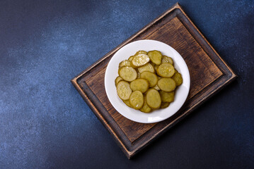 Delicious salted, canned cucumbers cut into slices on a white ceramic plate