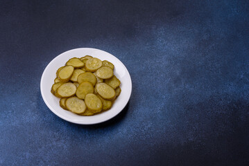 Delicious salted, canned cucumbers cut into slices on a white ceramic plate