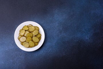 Delicious salted, canned cucumbers cut into slices on a white ceramic plate