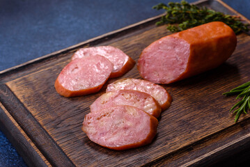 Delicious fresh smoked sausages cut with slices on a wooden cutting board