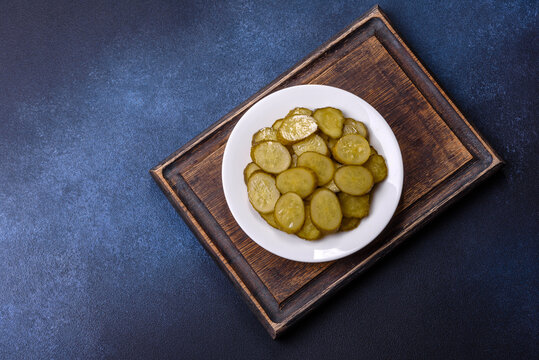 Delicious salted, canned cucumbers cut into slices on a white ceramic plate
