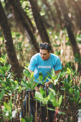 Portrait of caucasian man wearing volunteer blue t-shirt ,environment conservation,volunteering help to pick up plastic and foam garbage on mangrove forest park area and ocean beach.