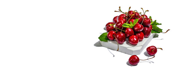 Ripe sweet cherries with fresh mint leaves isolated on white background. Trendy beton stand