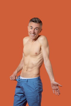 A man in shorts with flat belly looking emotional and surprised