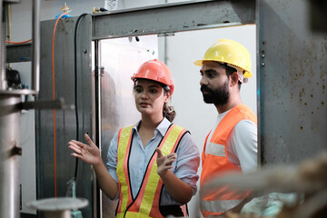 engineer worker working together with safety uniform and white helmet to work in industry factory handle tablet. Factory worker inspecting production line of drink production in factory. indian men