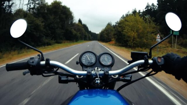 Motorcycle adventure, ride on asphalt forest road in autumn. First-person view.
