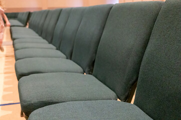 selective focus on a padded seat cushion of a row of chairs in a auditorium. 