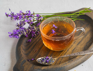 Lavender tea in transparent glass cups on a wooden tray on a light concrete background. Hot drinks.