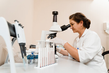 Laboratory assistant looks into microscope and makes blood test in the laboratory. Medical...