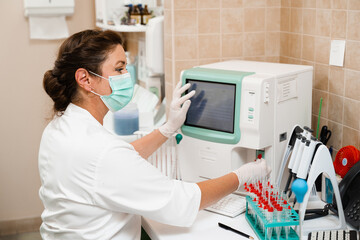 Laboratory assistant works on blood analyzer and makes hematological analysis in the laboratory. Medical equipment in the lab. Biochemical and hematological analysis of blood.