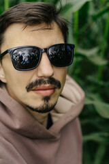 Large male portrait. A man in dark glasses with a mustache and beard.