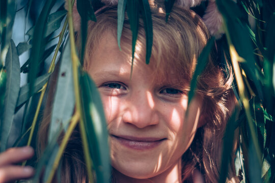 little child portrait in green spring nature by the tree willow with long green limbs